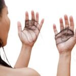 Woman experiencing hair loss while checking hair strands in mirror